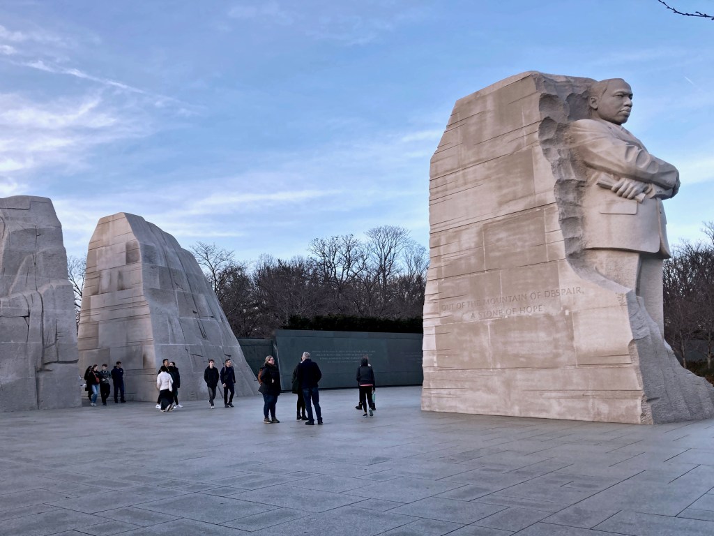 É como a foto anterior, mas vista de outro ângulo. Num fim de tarde encontram-se três maciços de mármore (ou rocha parecida). É como se um dos maciços tivesse saído dos outros dois. Nele encontra-se encravada a figura de Luther King.
